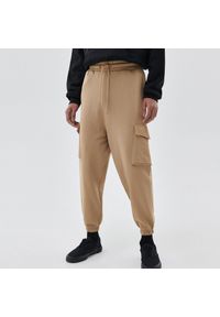 Cropp - Dresowe spodnie z kieszeniami cargo - Beżowy. Kolor: beżowy. Materiał: dresówka