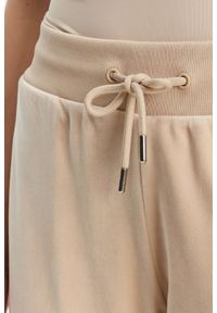 Guess - GUESS Beżowe damskie spodnie dresowe Couture. Kolor: beżowy. Materiał: dresówka #5