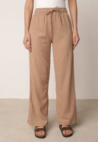 Born2be - Beżowe Szerokie Spodnie z Teksturalnej Tkaniny z Wiązaniem w Pasie Agatia. Okazja: do pracy, na co dzień, na spacer. Stan: podwyższony. Kolor: beżowy. Materiał: tkanina. Długość: długie. Styl: wakacyjny, casual #3
