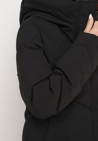 Born2be - Czarna Kurtka Pikowana o Długim Fasonie z Nieodpinanym Kapturem i Kieszeniami Nerilani. Okazja: na spacer, na co dzień. Kolor: czarny. Materiał: skóra. Długość: długie. Sezon: zima. Styl: casual, elegancki #5