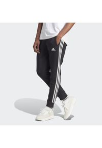 Adidas - Spodnie Essentials Fleece 3-Stripes Tapered Cuff. Kolor: wielokolorowy, czarny, biały. Materiał: polar, materiał