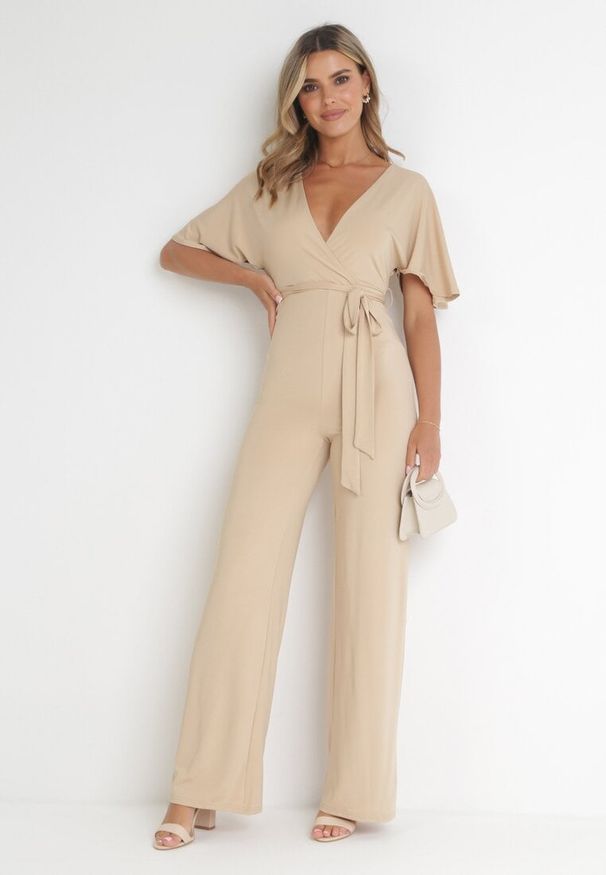 Born2be - Beżowy Długi Kombinezon z Kopertowym Dekoltem i Ozdobnym Wiązaniem Abrarani. Okazja: na spotkanie biznesowe. Kolor: beżowy. Długość: długie. Styl: elegancki, biznesowy