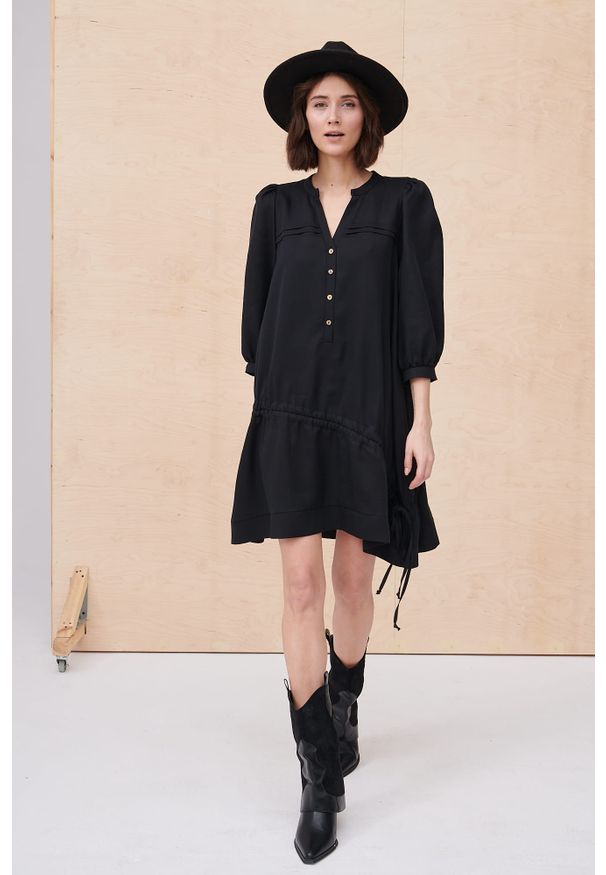 blue shadow - Sukienka Surri BS Czarny. Typ kołnierza: dekolt w serek. Kolekcja: plus size. Kolor: czarny. Wzór: aplikacja. Typ sukienki: asymetryczne, koszulowe, dla puszystych. Materiał: skóra, materiał, tkanina. Długość rękawa: krótki rękaw. Sezon: wiosna. Długość: mini