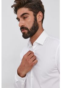 Calvin Klein Koszula męska kolor biały slim z kołnierzykiem klasycznym. Typ kołnierza: kołnierzyk klasyczny. Kolor: biały. Materiał: bawełna, tkanina. Długość rękawa: długi rękaw. Długość: długie. Wzór: gładki. Styl: klasyczny