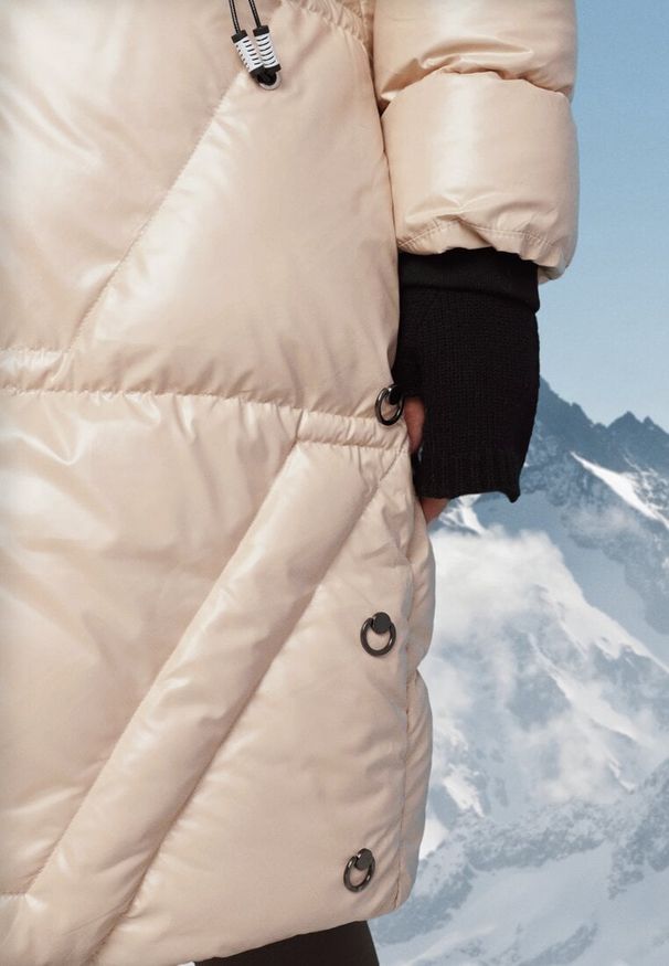 Born2be - Jasnobeżowa Pikowana Kurtka o Długim Kroju z Kapturem i Futrzanym Kołnierzem Semirielin. Okazja: na co dzień. Typ kołnierza: kaptur. Kolor: beżowy. Materiał: futro. Długość: długie. Wzór: aplikacja. Sezon: zima. Styl: casual, elegancki