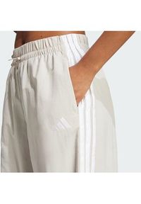 Adidas - adidas Spodnie dresowe Essentials 3-Stripes JC8168 Beżowy Loose Fit. Kolor: beżowy. Materiał: syntetyk #2