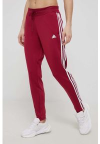 Adidas - adidas spodnie treningowe damskie kolor bordowy dopasowane high waist. Stan: podwyższony. Kolor: czerwony. Materiał: skóra, poliester, dzianina, materiał. Wzór: ze splotem