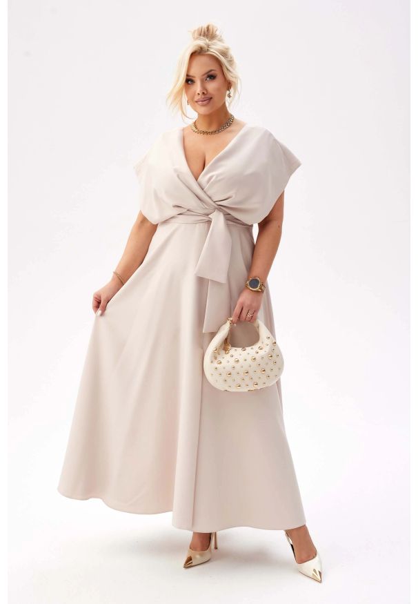 Moda Size Plus Iwanek - Elegancka beżowa sukienka Flavia na wesele PLUS SIZE XXL. Okazja: na wesele, na ślub cywilny. Typ kołnierza: dekolt kopertowy. Kolekcja: plus size. Kolor: beżowy. Materiał: elastan, tkanina, poliester. Typ sukienki: dla puszystych. Styl: elegancki