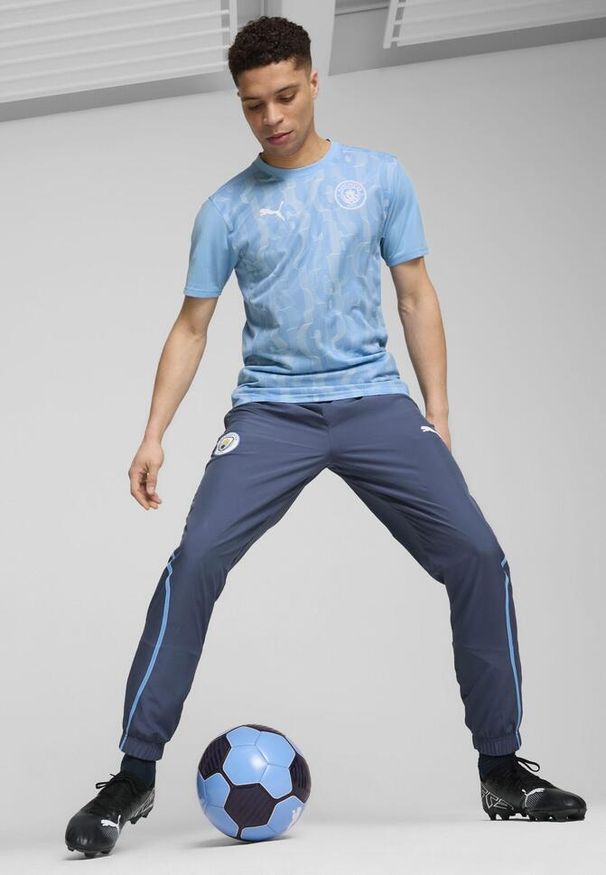Puma - Męska koszulka przedmeczowa z krótkim rękawem Manchester City PUMA. Kolor: biały, wielokolorowy, niebieski. Długość rękawa: krótki rękaw. Długość: krótkie