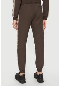 Guess - GUESS Brązowe męskie spodnie dresowe z lampasami Mickey, Rozmiar S. Kolor: brązowy. Materiał: dresówka #2