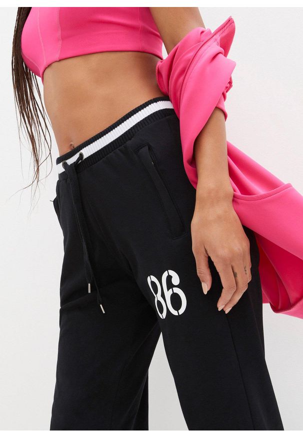 bonprix - Spodnie dresowe z elastycznego materiału z bawełną. Kolor: czarny. Materiał: bawełna, materiał, dresówka. Wzór: nadruk. Styl: sportowy