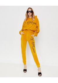 JOANNA MUZYK - Aksamitne spodnie z logo. Stan: podwyższony. Kolor: żółty. Materiał: dresówka. Wzór: aplikacja