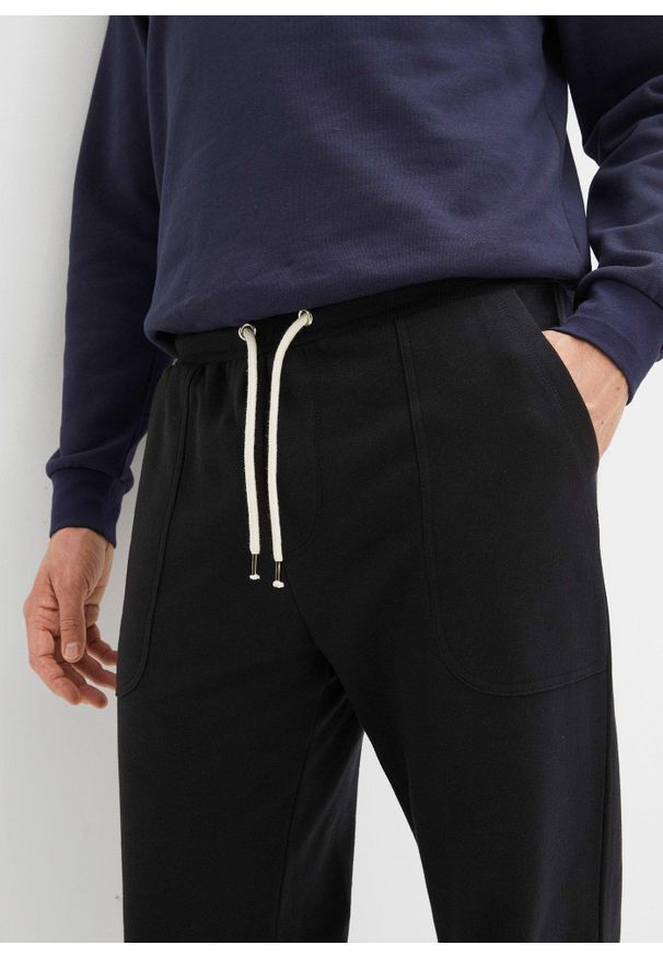 bonprix - Spodnie sportowe z czystej bawełny organicznej. Stan: obniżony. Kolor: czarny. Materiał: dresówka, bawełna. Styl: sportowy