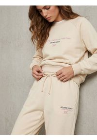 Sinsay - Spodnie regular jogger fleece z hafotwanym napisem NYC - kremowy. Kolor: kremowy. Wzór: napisy #1