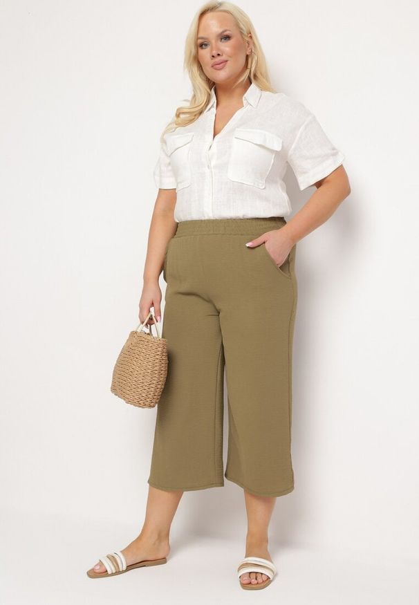 Born2be - Ciemnozielone Szerokie Spodnie z Wysokim Stanem z Gumką w Talii i Nogawkami Długości 3/4 Levolia. Okazja: na co dzień. Stan: podwyższony. Kolekcja: plus size. Kolor: zielony. Materiał: jedwab. Styl: casual, elegancki