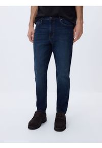 Reserved - Jeansy carrot slim z efektem sprania - granatowy. Kolor: niebieski