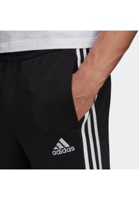 Adidas - Spodnie męskie adidas Essentials Tapered Cuff 3 Stripes. Kolor: czarny, biały, wielokolorowy. Materiał: wiskoza, poliester, bawełna. Wzór: paski. Sport: joga i pilates, fitness