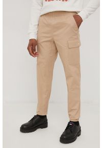 New Balance spodnie męskie kolor beżowy w fasonie cargo. Okazja: na co dzień. Kolor: beżowy. Materiał: bawełna, tkanina. Wzór: gładki. Styl: casual