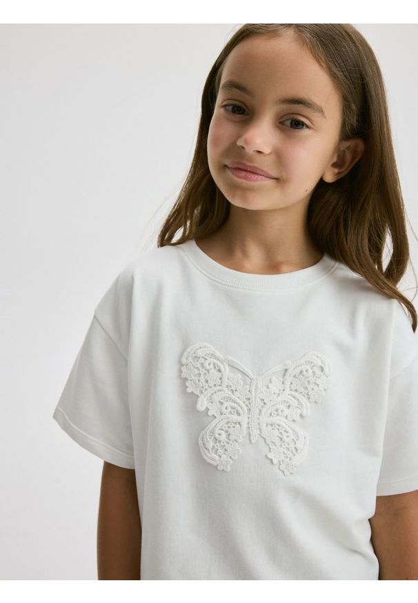 Reserved - T-shirt z naszywką - złamana biel. Materiał: bawełna. Wzór: aplikacja