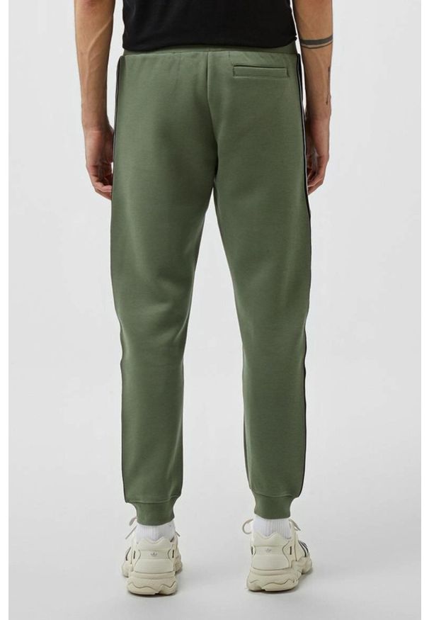 Guess - GUESS Zielone męskie spodnie dresowe z lampasami Mickey, Rozmiar XL. Kolor: zielony. Materiał: dresówka