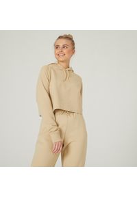 DOMYOS - Bluza z kapturem damska Nyamba Gym & Pilates 520 Crop. Typ kołnierza: kaptur. Kolor: beżowy. Materiał: dzianina, poliester, materiał, bawełna, włókno. Długość rękawa: długi rękaw. Długość: długie. Sport: joga i pilates