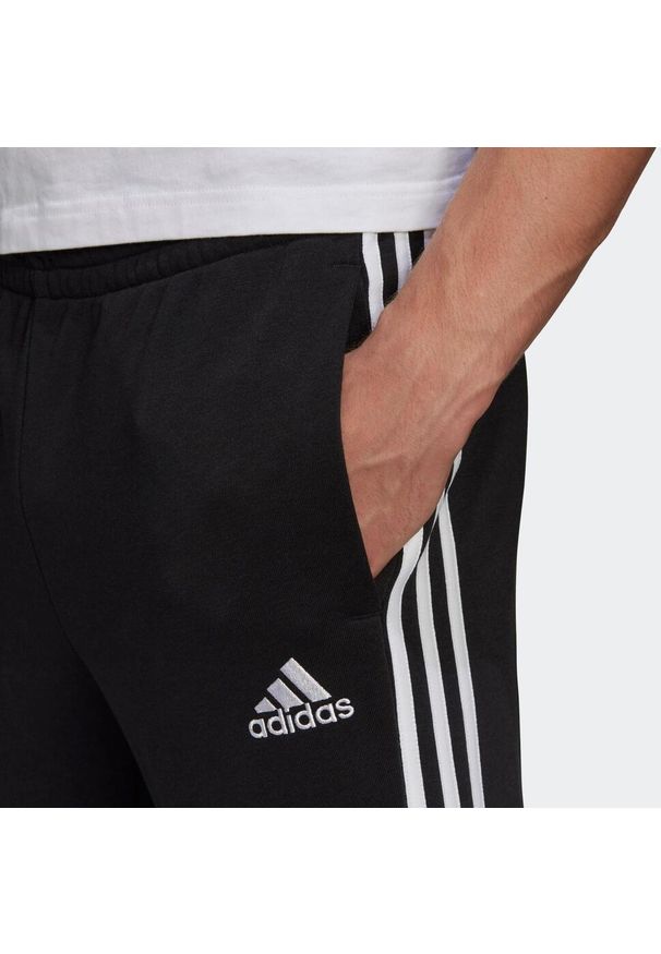 Adidas - Spodnie męskie adidas Essentials Tapered Cuff 3 Stripes. Kolor: czarny, biały, wielokolorowy. Materiał: wiskoza, poliester, bawełna. Wzór: paski. Sport: joga i pilates, fitness