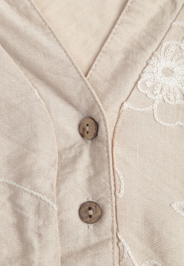 Born2be - Beżowa Bluzka Ozdobiona Guzikami i Haftowanymi Kwiatami Delmana. Okazja: na spacer, na uczelnię, na co dzień. Kolekcja: plus size. Kolor: beżowy. Materiał: tkanina, materiał. Wzór: aplikacja, haft, kwiaty. Sezon: lato. Styl: wakacyjny, boho, klasyczny, casual