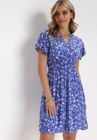 Born2be - Granatowa Kwiecista Sukienka Mini z Wiskozy z Marszczoną Gumką w Pasie Catela. Kolor: niebieski. Materiał: wiskoza. Długość rękawa: krótki rękaw. Wzór: kwiaty. Sezon: wiosna, lato. Typ sukienki: rozkloszowane, kopertowe. Długość: mini #1