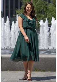 KARKO - Ekskluzywna sukienka weselna rozkloszowana zwiewna z falbanka na dekolcie DRACENA butelkowa zieleń PROMOCJA. Okazja: na wesele, na ślub cywilny. Typ kołnierza: dekolt w kształcie V, kokarda. Kolekcja: plus size. Materiał: szyfon, tkanina, poliester. Długość rękawa: krótki rękaw. Wzór: aplikacja. Sezon: lato. Typ sukienki: kopertowe, rozkloszowane, dla puszystych. Styl: wizytowy, elegancki #1