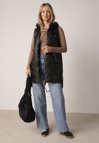 Born2be - Czarna Przejściowa Kamizelka Pikowana o Długim Kroju z Kapturem i Naszywką Harmaste. Okazja: na co dzień. Typ kołnierza: kaptur. Kolor: czarny. Materiał: jeans. Długość: długie. Wzór: aplikacja. Styl: casual #2