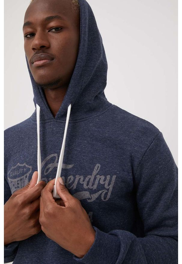 Superdry bluza męska kolor granatowy z kapturem z nadrukiem. Okazja: na co dzień. Typ kołnierza: kaptur. Kolor: niebieski. Wzór: nadruk. Styl: casual