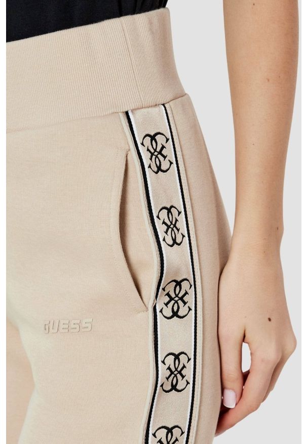 Guess - GUESS Beżowe spodnie dresowe damskie Britney. Kolor: beżowy. Materiał: dresówka