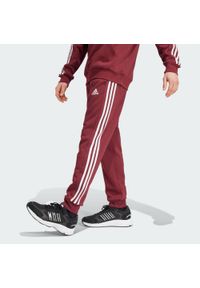 Adidas - Spodnie Essentials Fleece 3-Stripes Tapered Cuff. Kolor: czerwony. Materiał: polar, materiał