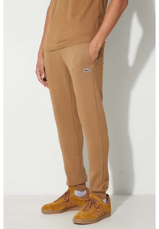 Lacoste spodnie dresowe męskie kolor brązowy gładkie. Kolor: brązowy. Materiał: dresówka. Wzór: gładki
