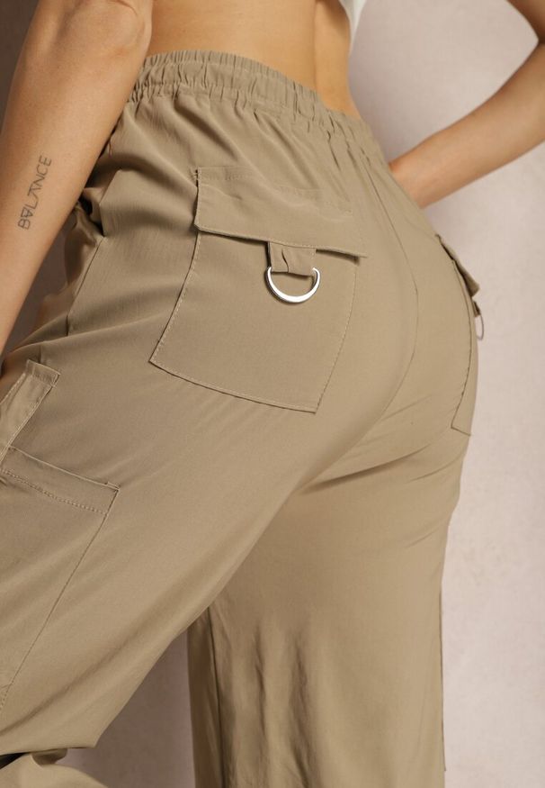 Renee - Ciemnobeżowe Szerokie Spodnie High Waist w Stylu Bojówek Wykończone Gumką w Talii Ellcara. Okazja: na co dzień. Stan: podwyższony. Kolor: beżowy. Materiał: satyna. Wzór: moro. Styl: elegancki, wizytowy, sportowy, militarny, casual