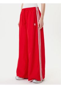 Adidas - adidas Spodnie dresowe adicolor Firebird JD3388 Czerwony Loose Fit. Kolor: czerwony. Materiał: syntetyk