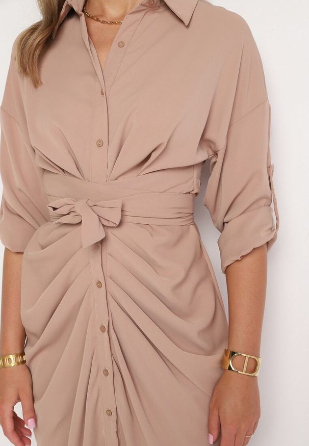 Born2be - Ciemnobeżowa Sukienka Koszulowa z Wiązanym Paskiem i Marszczeniem Hinula. Kolor: beżowy. Materiał: tkanina, materiał. Wzór: jednolity, gładki. Typ sukienki: koszulowe. Styl: elegancki. Długość: midi