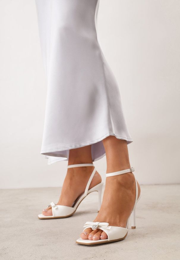Born2be - Białe Eleganckie Sandały VICES na Szpilce z Kokardą i Aplikacją z Cyrkoniami Melirea. Okazja: do pracy, na spotkanie biznesowe. Zapięcie: pasek. Kolor: biały. Wzór: aplikacja. Obcas: na szpilce. Styl: elegancki