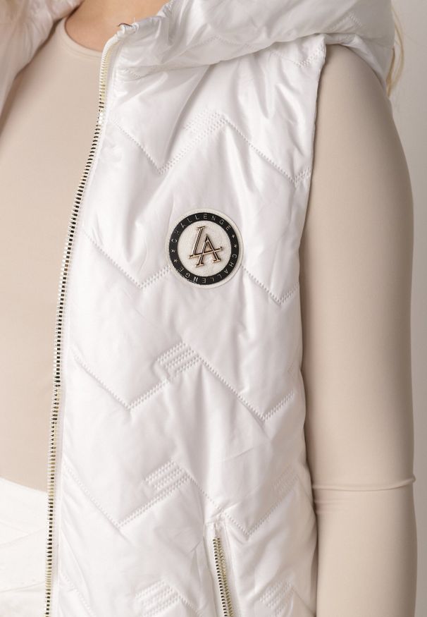 Born2be - Biała Przejściowa Kamizelka Pikowana o Długim Kroju z Kapturem i Naszywką Harmaste. Okazja: na co dzień. Typ kołnierza: kaptur. Kolor: biały. Materiał: jeans. Długość: długie. Wzór: aplikacja. Styl: casual