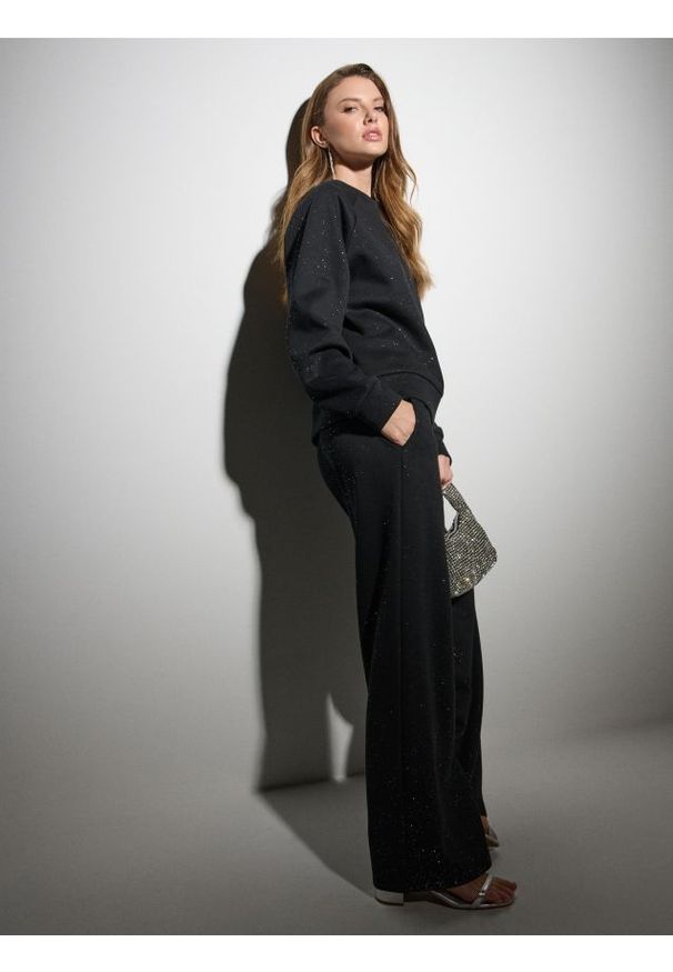 Sinsay - Dresowe spodnie z szeroką nogawką i brokatem - czarny. Kolor: czarny. Materiał: dresówka