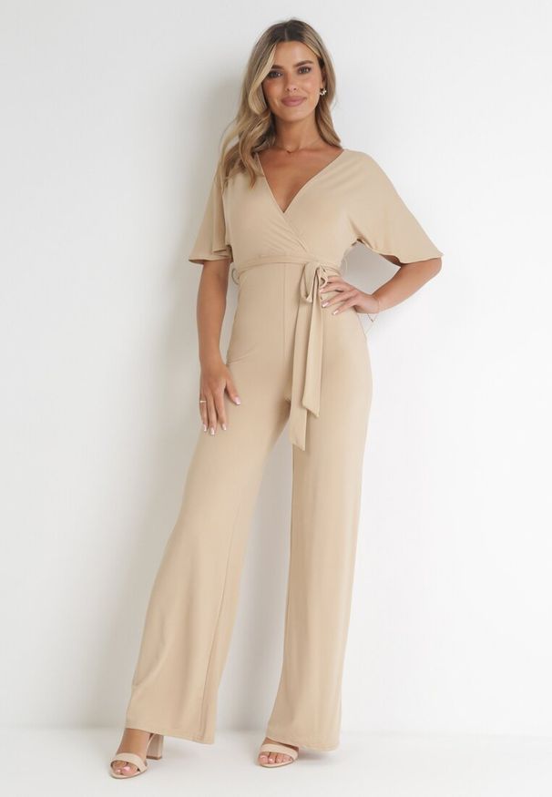 Born2be - Beżowy Długi Kombinezon z Kopertowym Dekoltem i Ozdobnym Wiązaniem Abrarani. Okazja: na spotkanie biznesowe. Kolor: beżowy. Długość: długie. Styl: biznesowy, elegancki