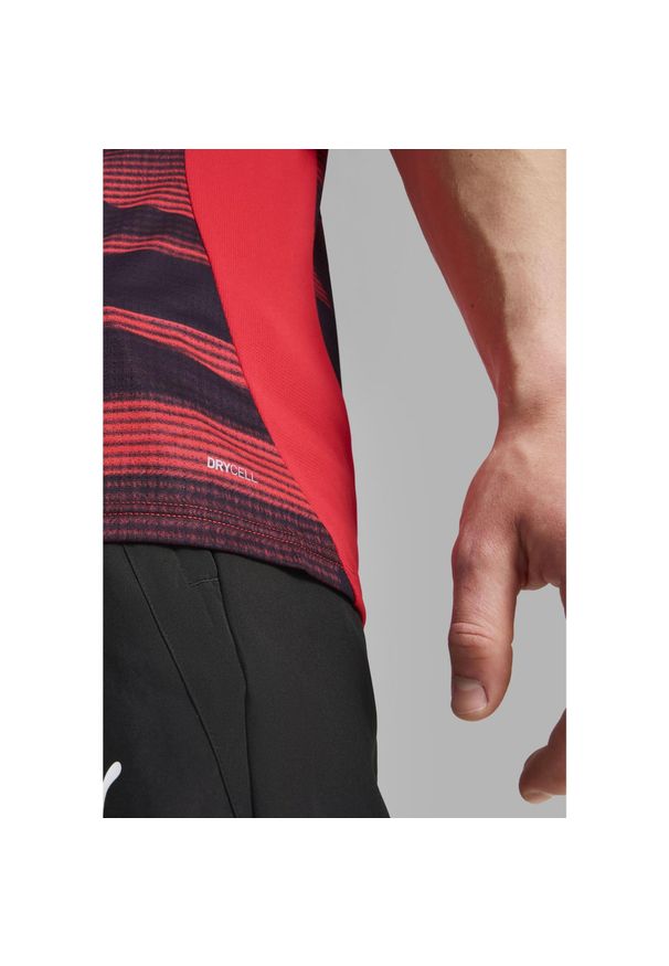 Puma - Męska koszulka przedmeczowa z krótkim rękawem AC Milan PUMA. Kolor: czerwony, wielokolorowy, czarny. Długość rękawa: krótki rękaw. Długość: krótkie