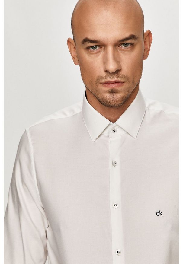 Calvin Klein - Koszula bawełniana. Typ kołnierza: kołnierzyk klasyczny. Kolor: biały. Materiał: bawełna. Długość rękawa: długi rękaw. Długość: długie. Wzór: gładki. Styl: elegancki, klasyczny