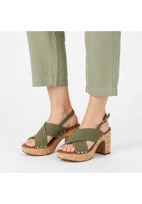 Sandały damskie Marco Tozzi, na wysokim słupku z krzyżowanymi paskami i regulowanym zapięciem przy pięcie osadzone na platformie o korkowym wykończen. Zapięcie: pasek. Kolor: zielony. Materiał: len. Wzór: paski. Sezon: lato. Obcas: na platformie. Styl: elegancki, klasyczny. Wysokość obcasa: średni #1