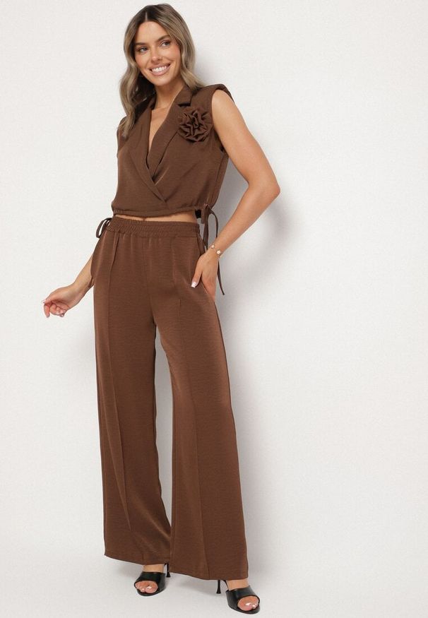 Born2be - Brązowy Komplet Kopertowa Bluzka z Kwiatową Broszką i Szerokie Spodnie Reavilia. Kolor: brązowy. Wzór: kwiaty
