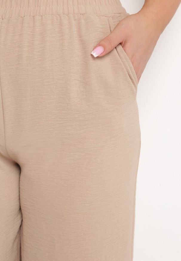 Born2be - Ciemnobeżowe Szerokie Spodnie z Wysokim Stanem z Gumką w Talii i Nogawkami Długości 3/4 Levolia. Okazja: na co dzień. Stan: podwyższony. Kolekcja: plus size. Kolor: beżowy. Materiał: jedwab. Styl: elegancki, casual