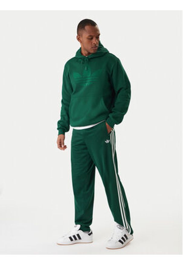 Adidas - adidas Spodnie dresowe Firebird KD8317 Zielony Loose Fit. Kolor: zielony. Materiał: syntetyk
