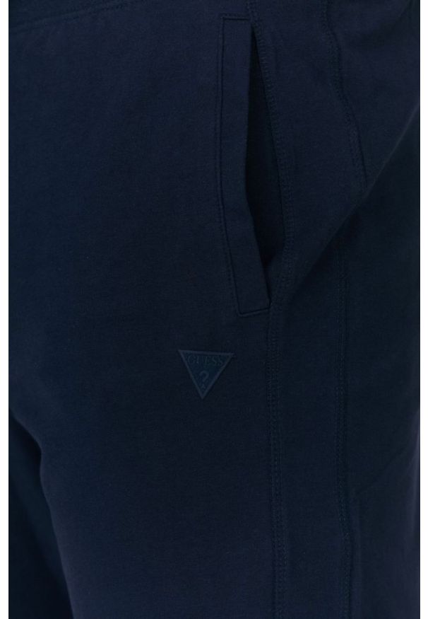 Guess - GUESS Granatowe męskie spodnie dresowe, Rozmiar XL. Kolor: niebieski. Materiał: dresówka, bawełna. Wzór: aplikacja