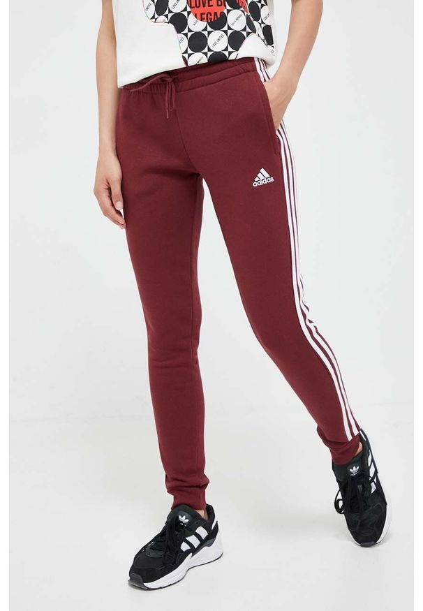 Adidas - adidas spodnie dresowe kolor bordowy z aplikacją. Kolor: czerwony. Materiał: dresówka. Wzór: aplikacja