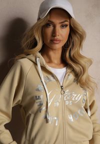Renee - Beżowy Komplet Dresowy Spodnie Ozdobione Napisami Bluza na Suwak z Kapturem Semiraella. Kolor: beżowy. Materiał: dresówka. Wzór: napisy, aplikacja. Sport: turystyka piesza, fitness
